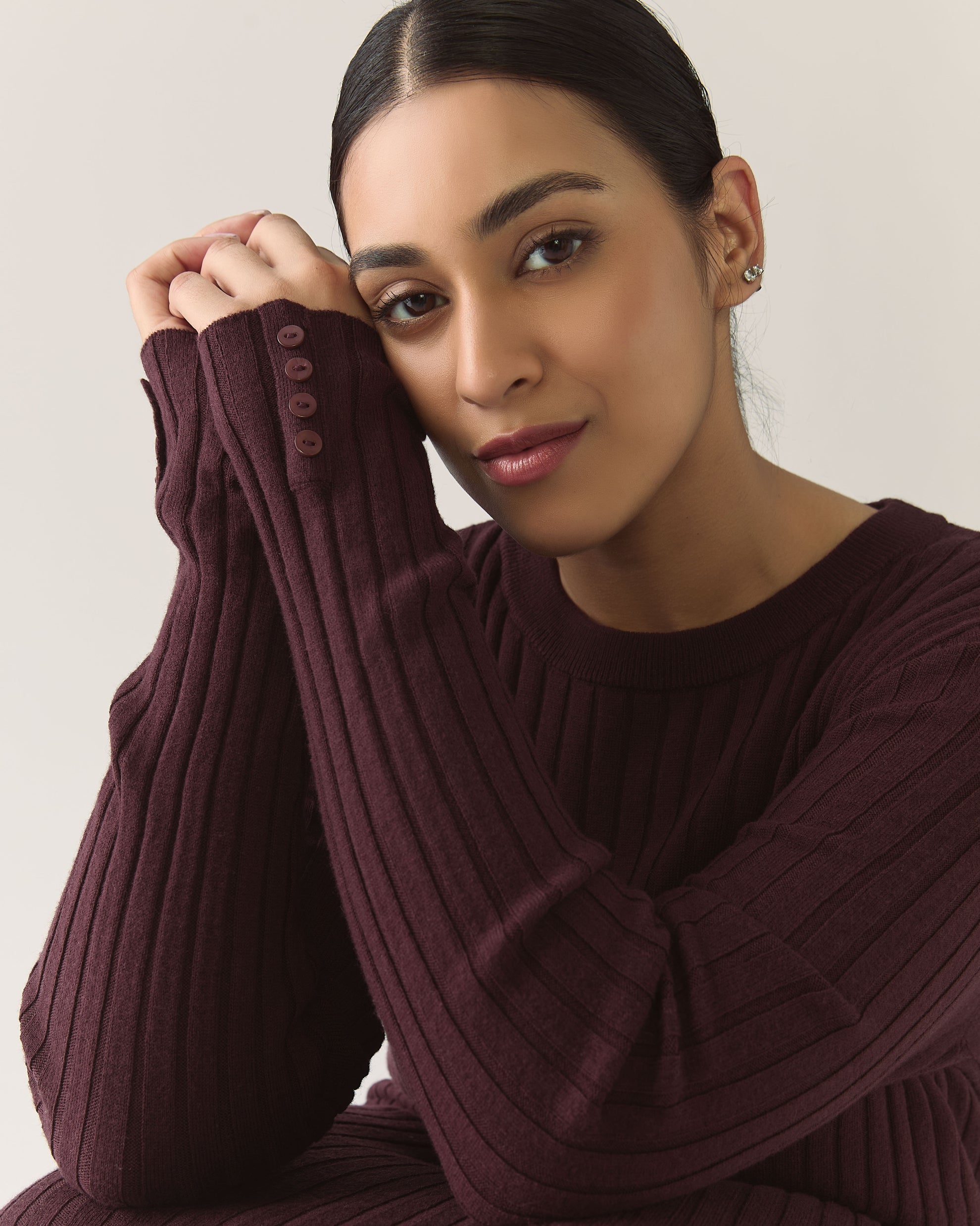 Woman wearing a burgundy plum ribbed sweater dress