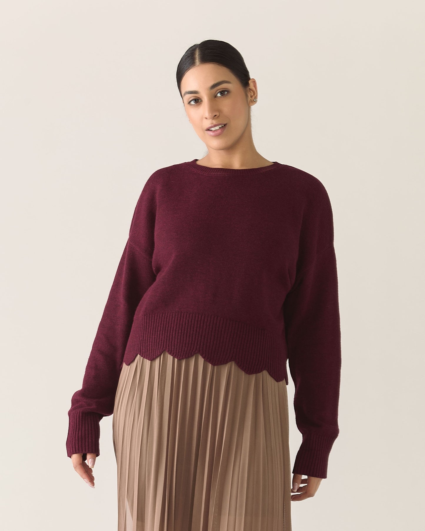 Woman wearing a burgundy zinfandel sweater and mocha brown pleated mesh skirt