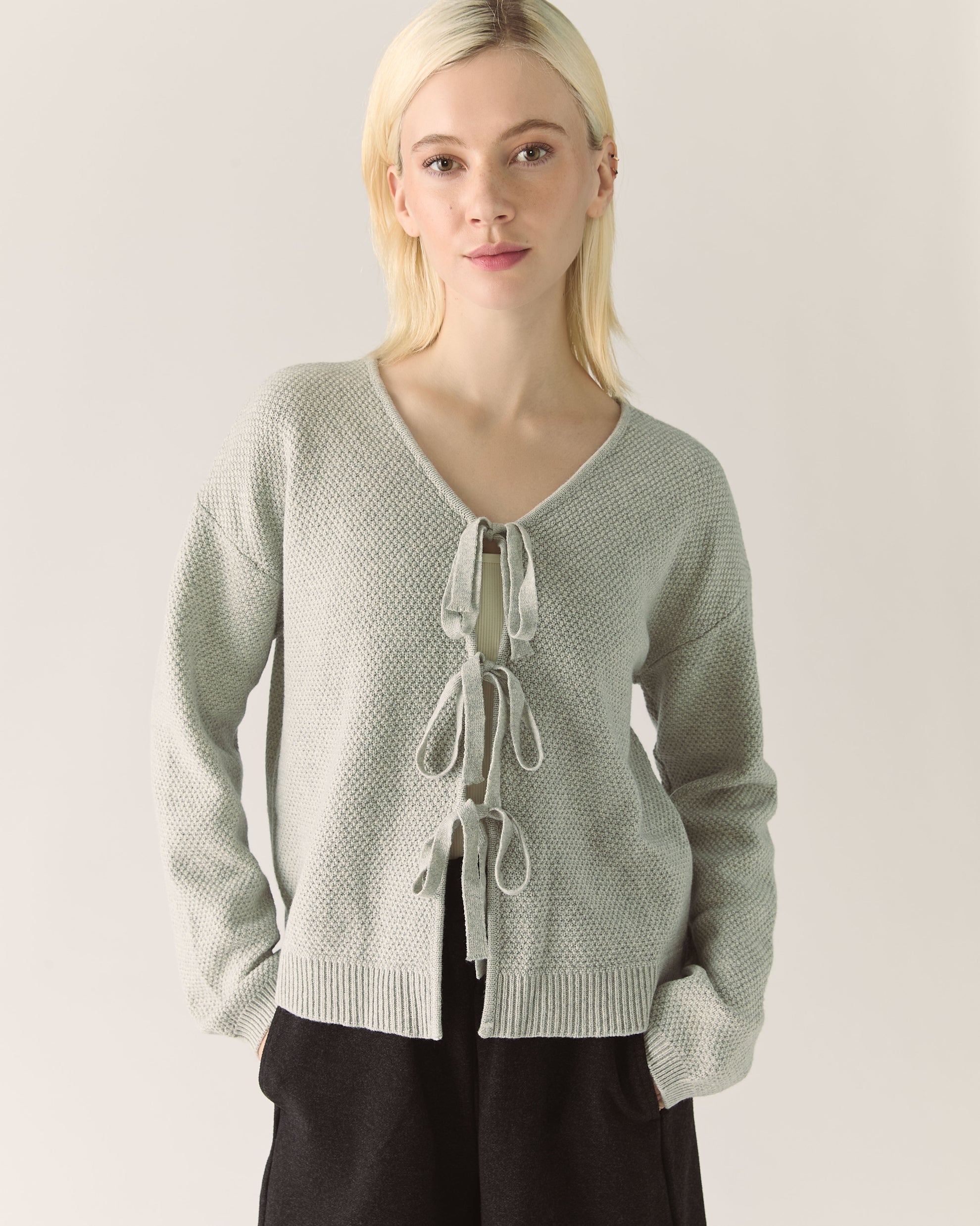 Woman wearing a light grey gray cardigan with lace-up front 