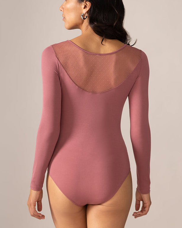 Woman wearing a mauve long-sleeve bodysuit with sheer mesh back on a beige background