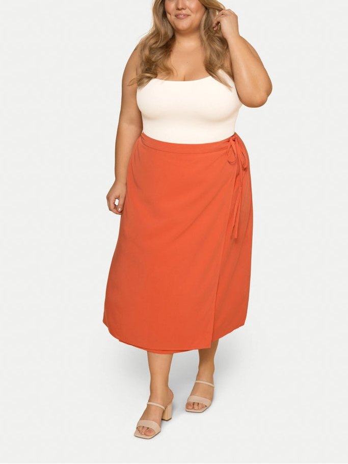Woman wearing a white top and orange skirt on a white background