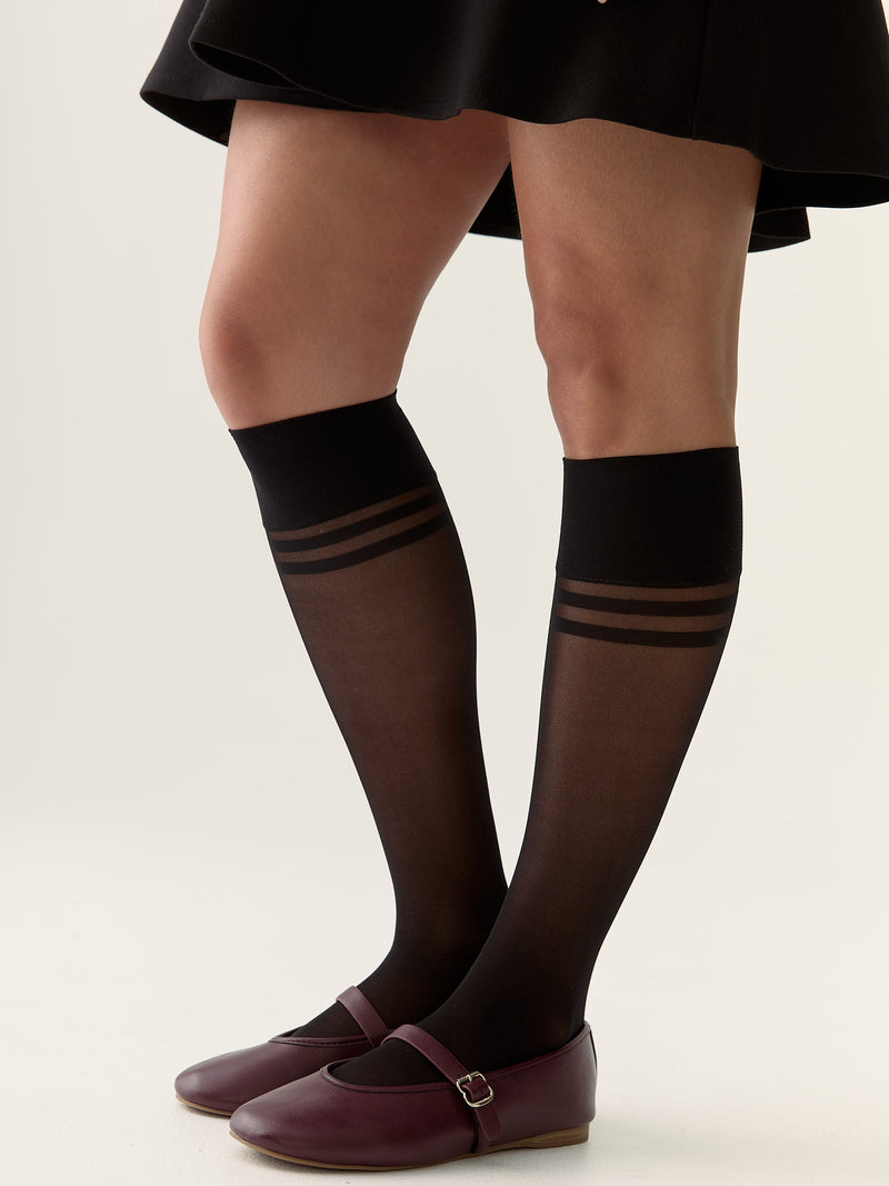 Black knee-high socks with striped design worn by a person on a plain background